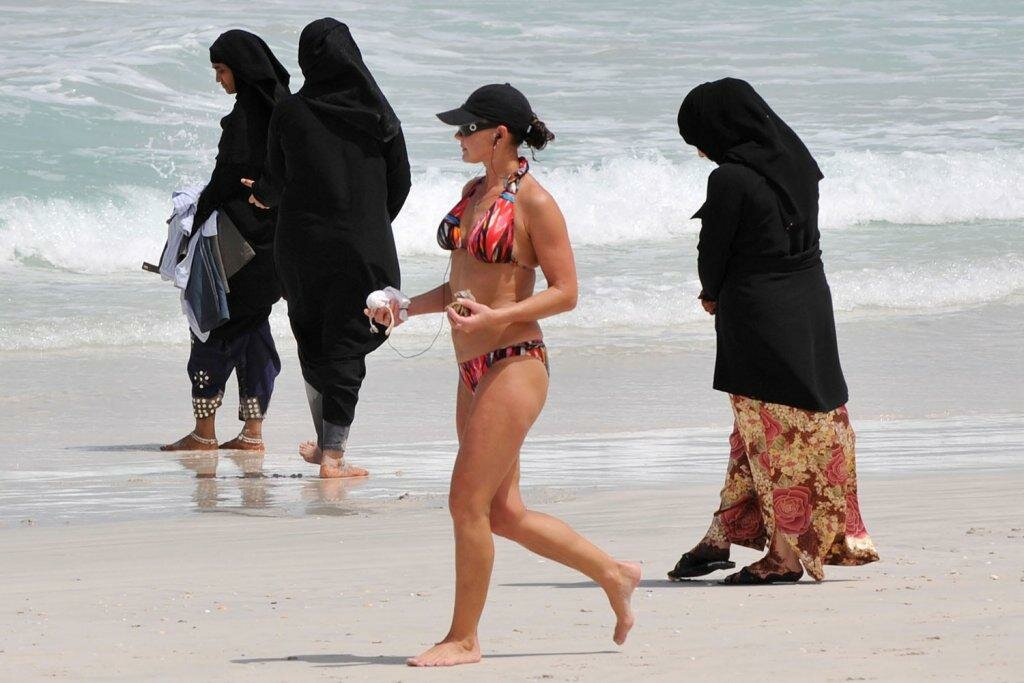 На пляже в ОАЭ: мусульманки в буркини, туристка в бикини